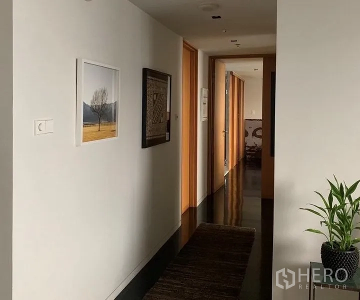 公寓 出售在Sathon, Bangkok - 走廊悬挂艺术画作，木质门与深色地面铺地毯。