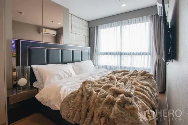 Condominium for rent in Phra Khanong, Bangkok - Master bedroom with upholstered headboard, large window and soft bedding.