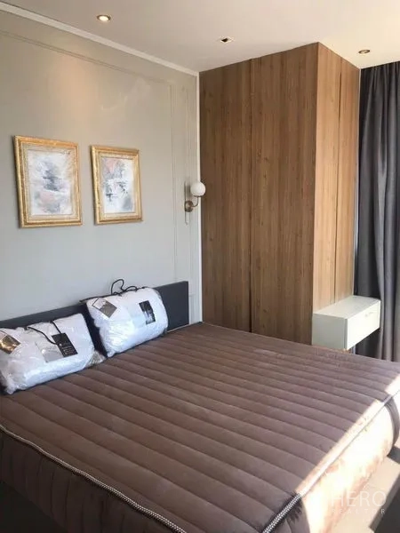 คอนโด ให้เช่าในBang Rak, Bangkok - ห้องนอนสว่าง ผนังไม้ตกแต่ง โคมไฟข้างเตียง และกรอบภาพ