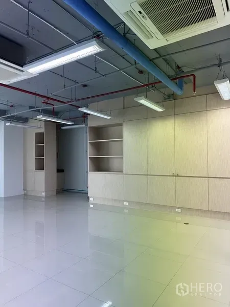 办公空间 出租在Khlong Toei, Bangkok - 一面墙的浅木色内置柜与搁架，工业风外露天花的现代办公室。