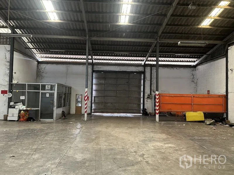 货栈 出租在Khan Na Yao, Bangkok - 仓库后侧内部，设大型卷闸门、小型玻璃办公室与储物区。