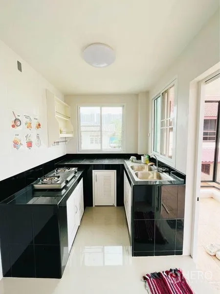 Home Office for rent in Bang Sue, Bangkok - Compact kitchen with black countertops, gas hob, sink and corner windows.