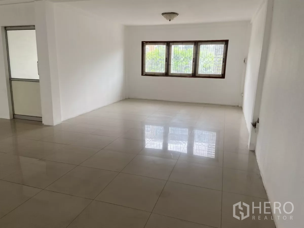 Shophouse for rent in Prawet, Bangkok - Bright upper-level room with corner windows and a glass door, tiled throughout.
