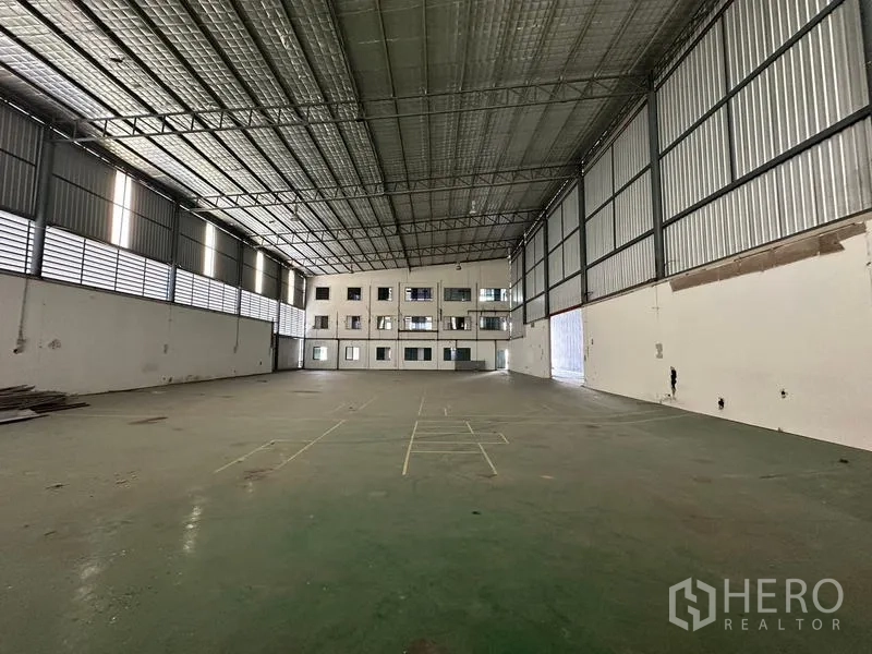 Warehouse for rent in Suan Luang, Bangkok - Warehouse interior facing a three‑storey office block and large loading doors.