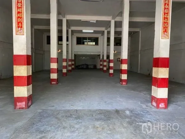 Warehouse for rent in Khlong Toei, Bangkok - Empty warehouse interior with tall concrete pillars painted red and white and a high ceiling.