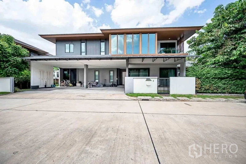 Detached House for sale in Prawet, Bangkok - Modern two-storey detached house in Prawet, Bangkok with wide carport and tall windows.