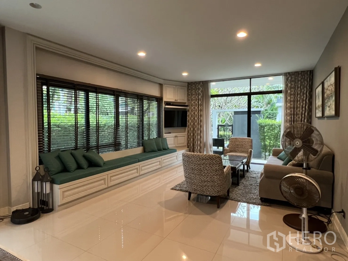 Detached House for rent or sale in Bang Kapi, Bangkok - Spacious lounge with built-in TV wall, long bench seat and sliding glass doors to the garden.