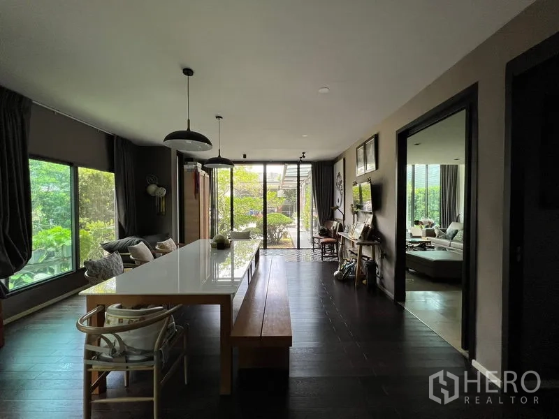 Detached House for sale in Bang Kapi, Bangkok - Dining area with a long table, pendant lights and garden views through large windows.