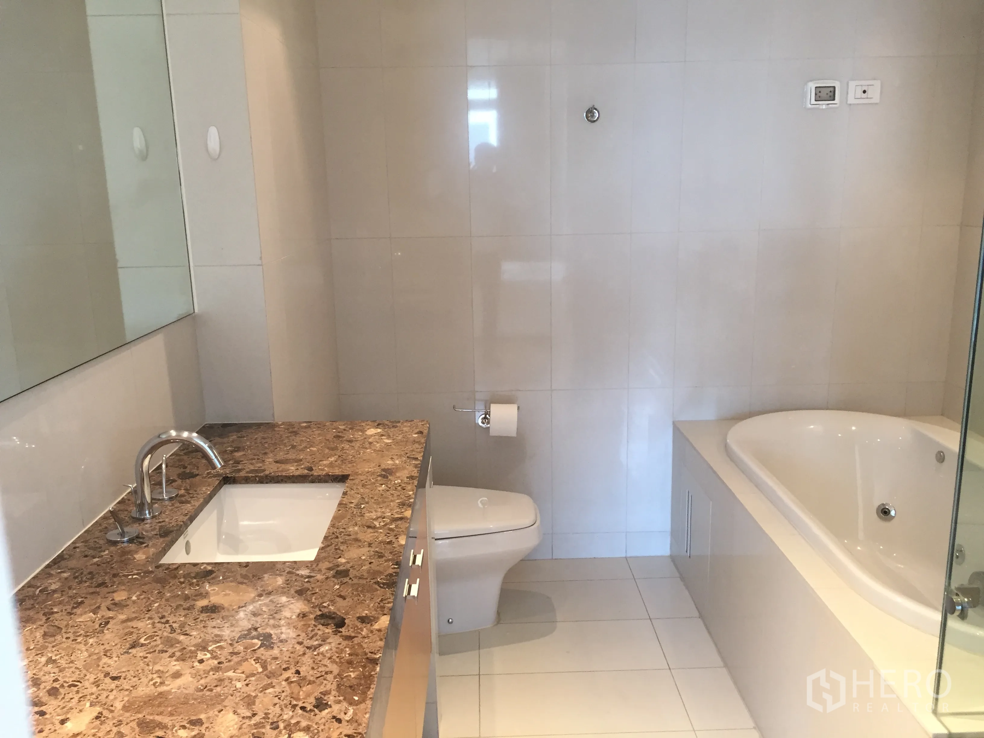 Condominium for rent in Pathum Wan, Bangkok - Bright bathroom with marble vanity, bathtub and tiled walls.