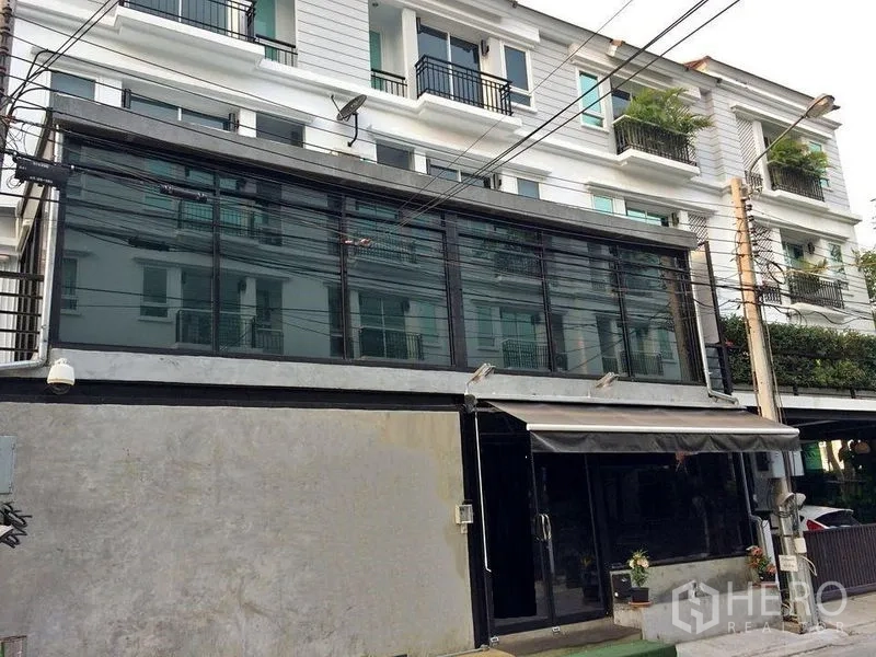 联排别墅 出售在Wang Thonglang, Bangkok - 建筑正面，玻璃立面与遮阳篷及邻近住宅