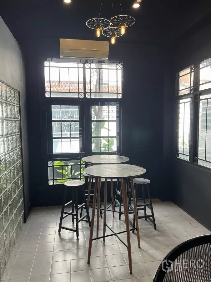 Home Office for rent in Wang Thonglang, Bangkok - Pantry or dining nook with high tables, pendant lights, and a glass-block wall.