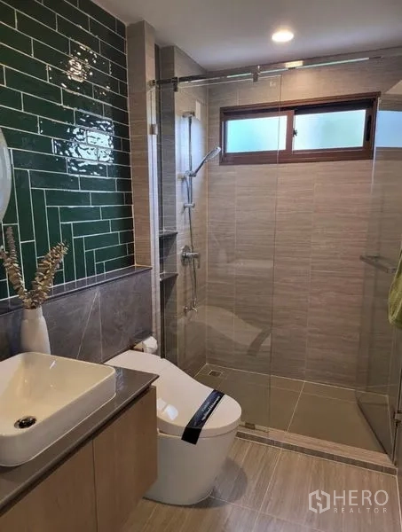 Detached House for rent in Bang Kapi, Bangkok - Stylish bathroom with green tile feature wall and glass shower enclosure.