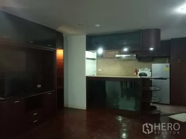 Condominium for rent in Watthana, Bangkok - Open-plan living area with TV cabinet and a breakfast bar connecting to the fitted kitchen.