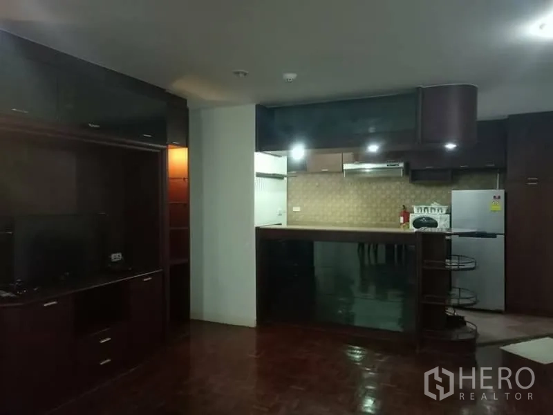 Condominium for rent in Watthana, Bangkok - Open-plan living area with TV cabinet and a breakfast bar connecting to the fitted kitchen.