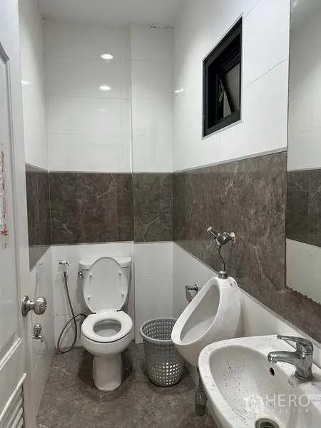 Factory for rent or sale in Bang Phli, Samut Prakan - Clean restroom with toilet, urinal, sink and wall tiles inside the factory.