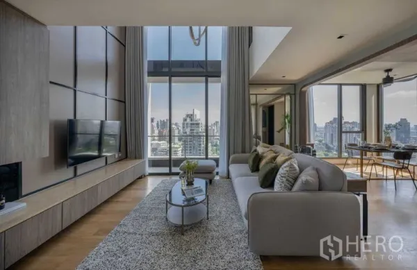 คอนโด ขายในKhlong Toei, Bangkok - ห้องนั่งเล่นกว้าง โซฟาและพรม หันสู่วิวเมืองผ่านผนังกระจกสูงจรดเพดาน