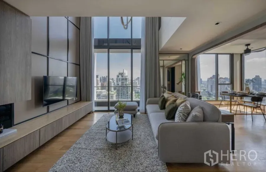 คอนโด ขายในKhlong Toei, Bangkok - ห้องนั่งเล่นกว้าง โซฟาและพรม หันสู่วิวเมืองผ่านผนังกระจกสูงจรดเพดาน