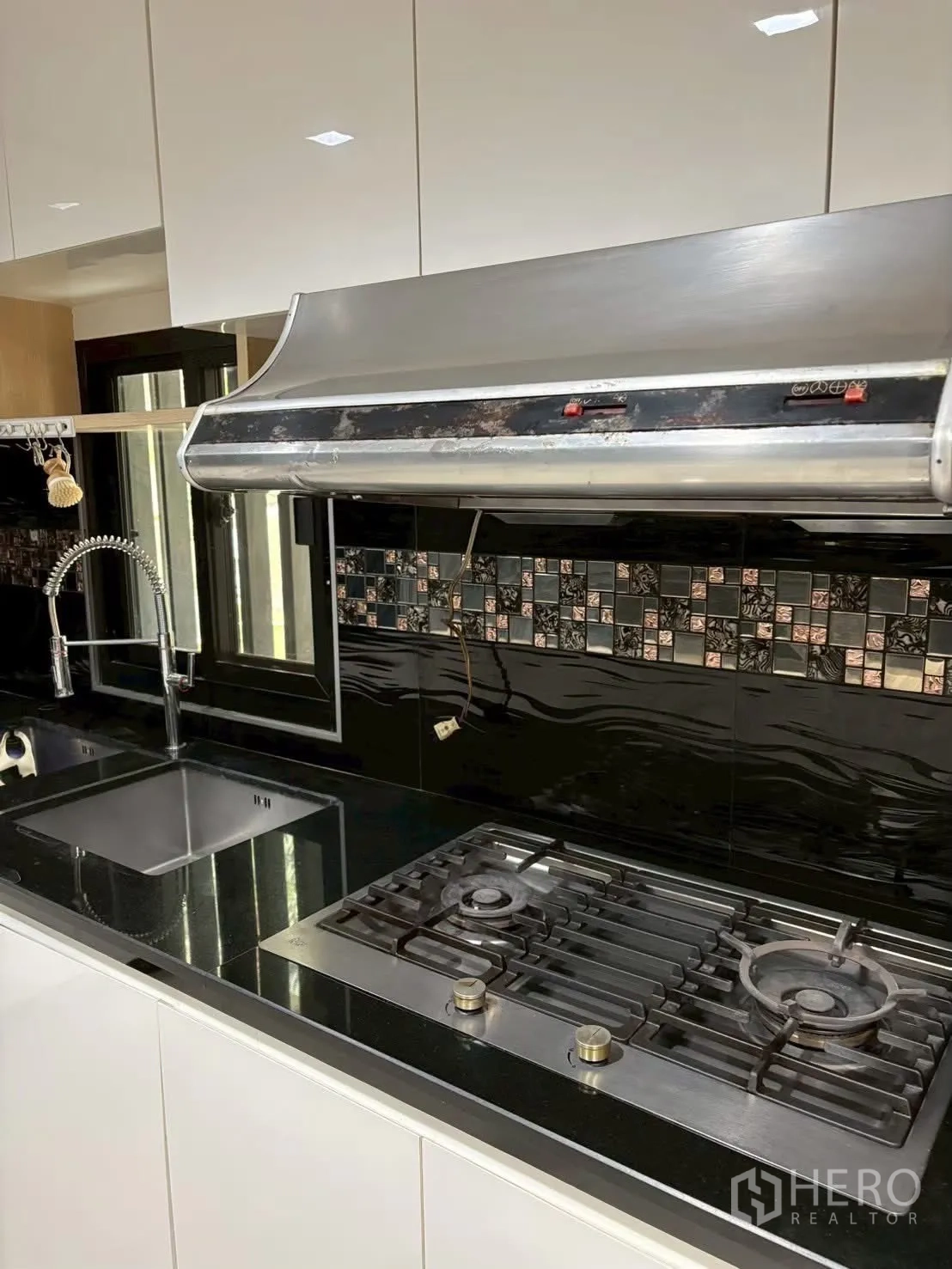 联排别墅 for rent in Pathum Wan, Bangkok - 厨房特写，燃气灶、水槽与不锈钢抽油烟机及黑色台面。