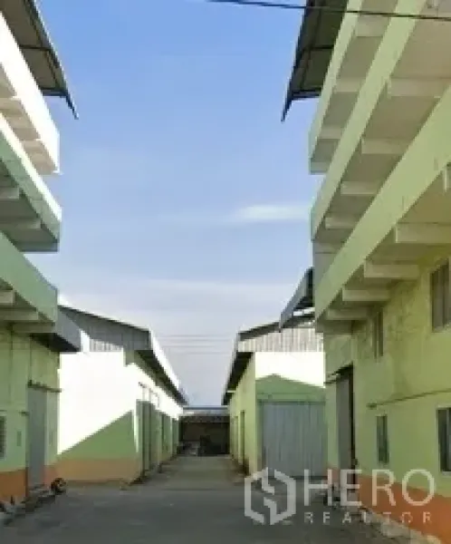 คลังสินค้า ให้เช่าในNonthaburi - ทางสัญจรระหว่างอาคารโกดังสีเขียวอ่อน หลังคาเมทัลชีท มีทางโหลดสินค้า ใต้ท้องฟ้าสดใส ในเขตบางกรวย นนทบุรี