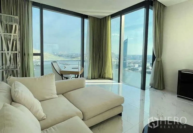 Condominium for rent or sale in Bangkok - Lounge corner with chaise sofa and panoramic corner glass overlooking the river.