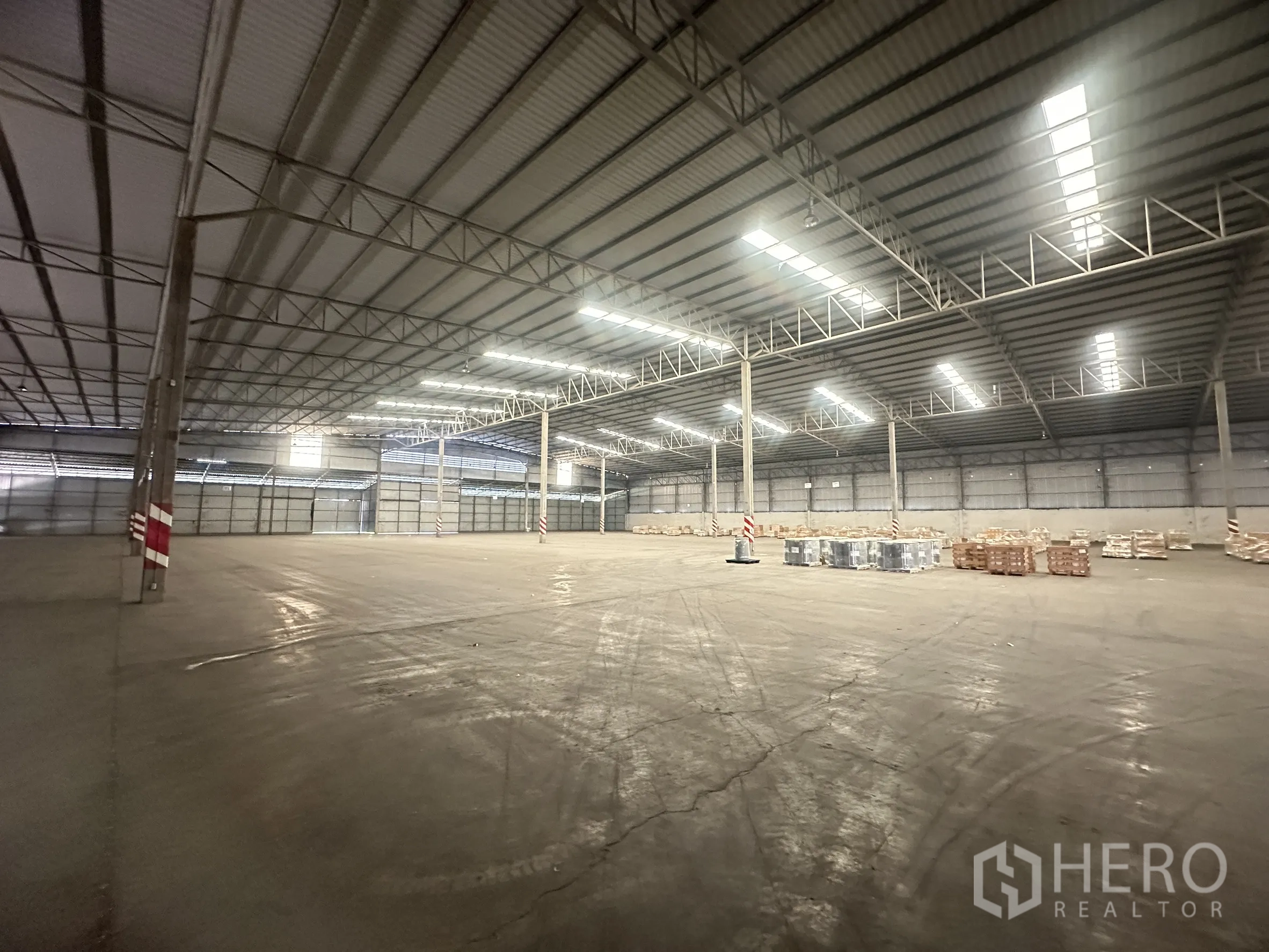 仓库 for rent in Bang Pa-in, Phra Nakhon Si Ayutthaya - 侧角度展示开阔地面、柱网与关闭的卷帘门。