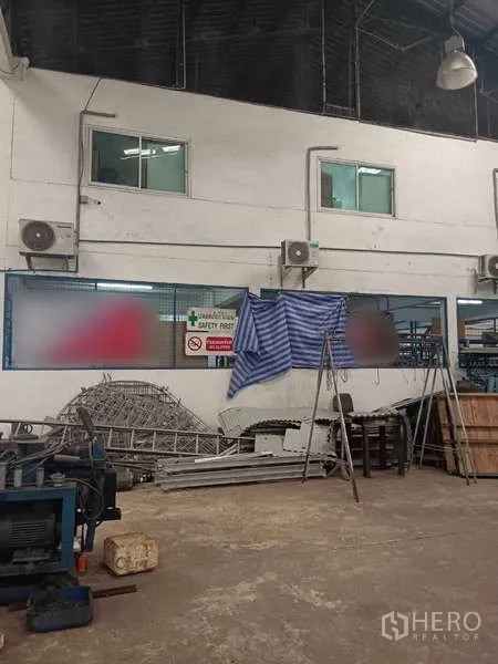 Warehouse for rent or sale in Nong Suea, Pathum Thani - Mezzanine windows and safety signage inside the industrial building.