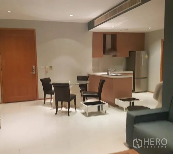 คอนโด ให้เช่าหรือขายในKhlong Toei, Bangkok - ครัวกะทัดรัดมีอ่างล้างจานบนไอส์แลนด์ ตู้เย็นสแตนเลส และชุดโต๊ะอาหาร 4 ที่นั่ง ใต้ไฟดาวน์ไลท์