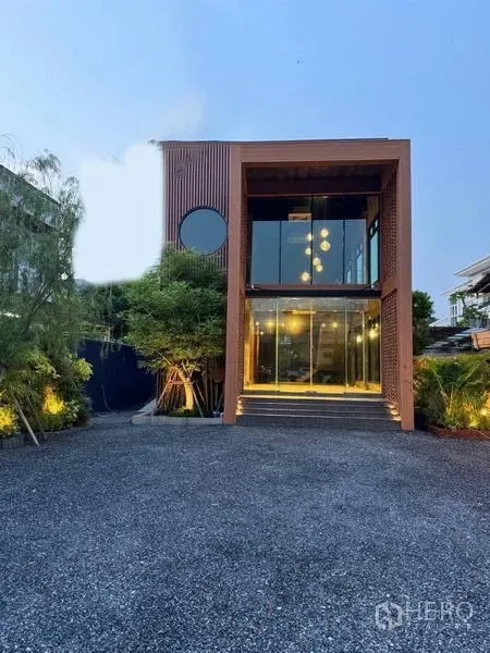 独立商业地产 出租在Sathon, Bangkok - 现代独栋建筑外观，通高玻璃立面、方盒结构、绿化与大面积碎石停车区。