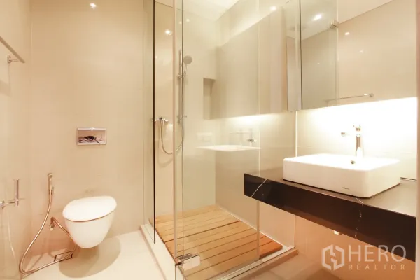 คอนโด ขายในBang Rak, Bangkok - ห้องน้ำสมัยใหม่ พร้อมห้องอาบน้ำกระจก โถสุขภัณฑ์แขวนผนัง และเคาน์เตอร์ล้างหน้าไฟส่องสว่าง
