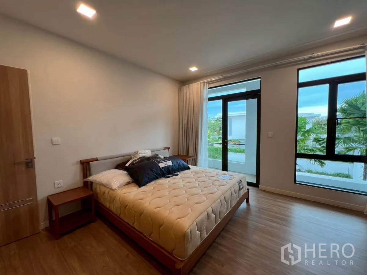 Detached House for rent in Samut Prakan - Bedroom with balcony access and wide windows bringing in natural light.