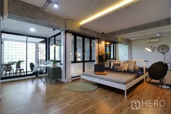 Townhouse for rent in Khlong Toei, Bangkok - Spacious bedroom with wood floors, large windows, glass partition and a work area.
