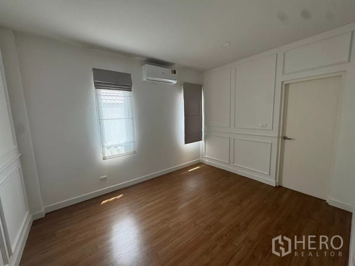 Detached House for rent or sale in Bang Bo, Samut Prakan - Air-conditioned bedroom with paneled walls, window blinds, and wood floor.