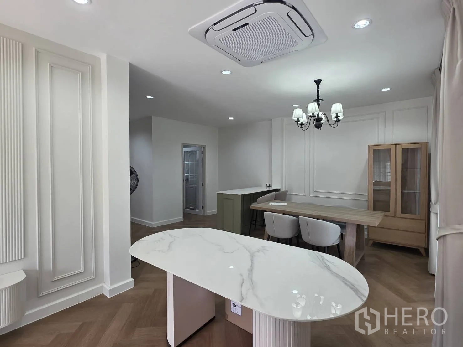 Detached House for sale in Lam Luk Ka, Pathum Thani - View to dining area with marble oval island, cassette AC, and chandelier lighting.