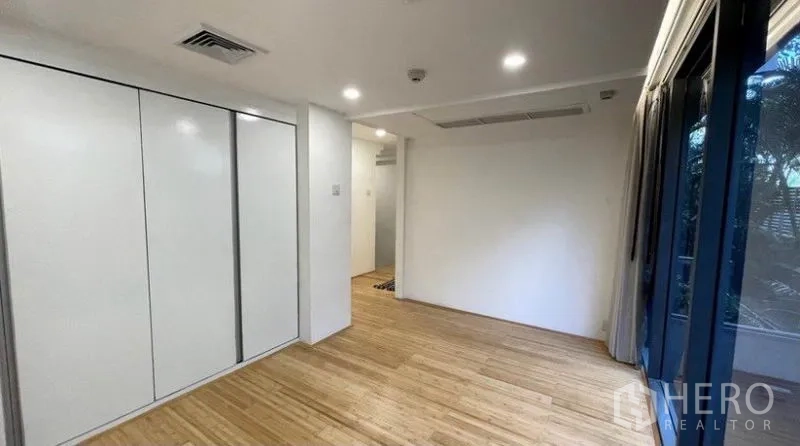 Condominium for rent in Watthana, Bangkok - Bedroom view showing fitted closets, recessed lighting, and garden-facing windows.