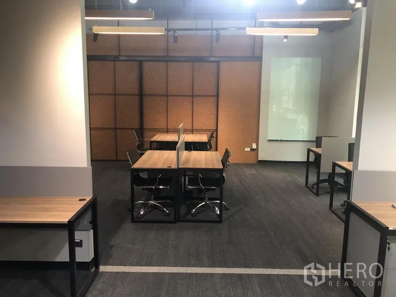 办公空间 出租在Watthana, Bangkok - 中央长条工位配隔板，地毯地面、玻璃白板与工业风吊灯。