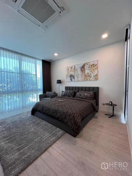 Detached House for sale in Samut Prakan - Bright bedroom with large windows, sheer curtains, and a dark upholstered bed.