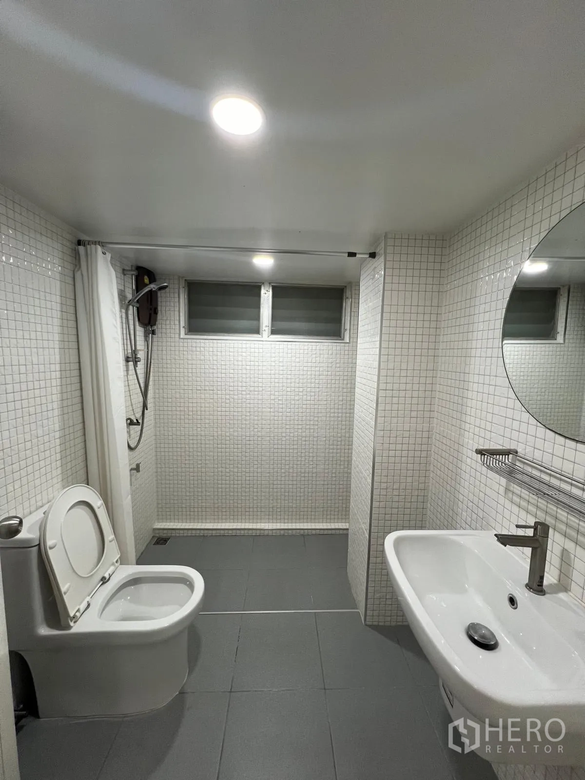 Detached House for rent in Saphan Sung, Bangkok - Modern bathroom with gray floor tiles, mosaic walls, walk-in shower, toilet and round mirror.