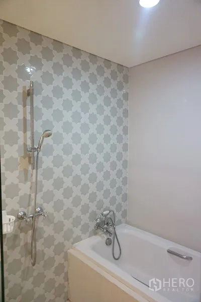 公寓 出售在Khlong Toei, Bangkok - 浴室设浴缸与手持花洒，几何纹理墙砖，曼谷空堤区公寓内。