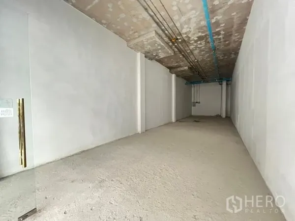 零售空间 出租在Khlong Toei, Bangkok - 狭长室内空间，层高充裕，顶面管线外露，白色批灰墙面。