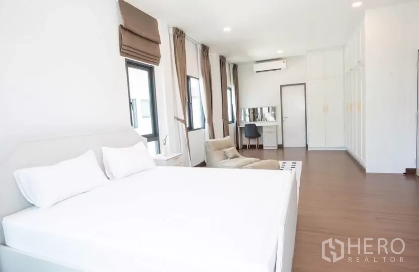 Detached House for rent in Bang Phli, Samut Prakan - Master bedroom view showing built-in wardrobes, vanity and wood flooring.