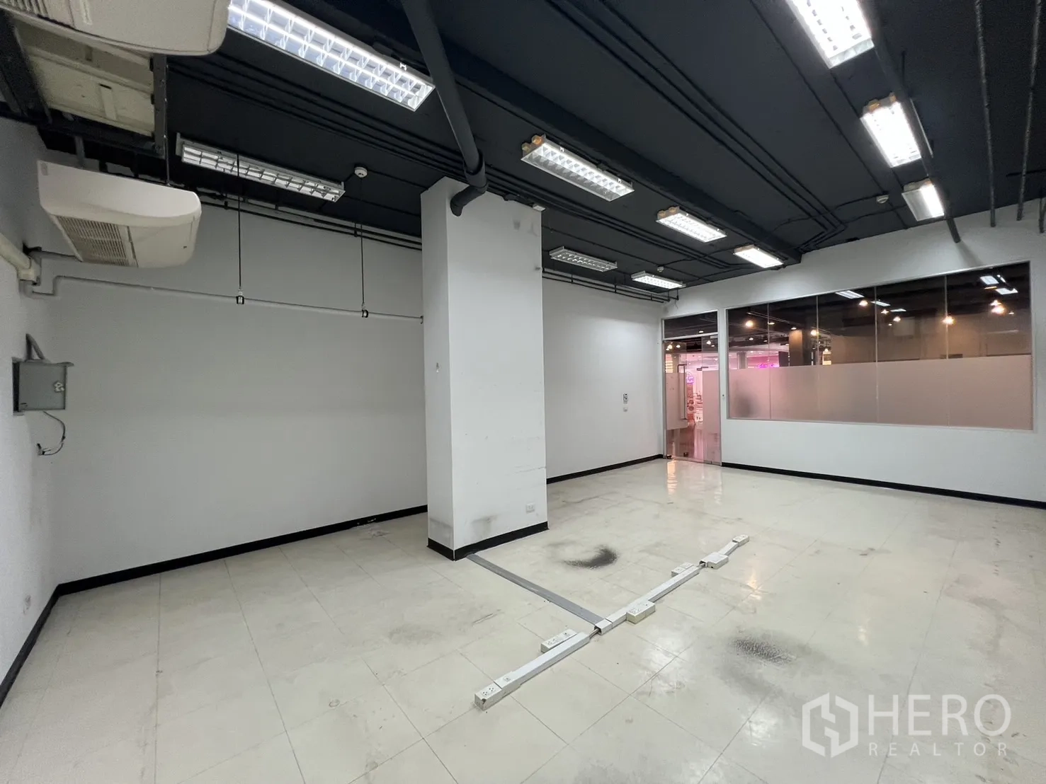 零售空间 出租 - 明亮的零售空间，荧光灯、玻璃隔断与地面电力走线。