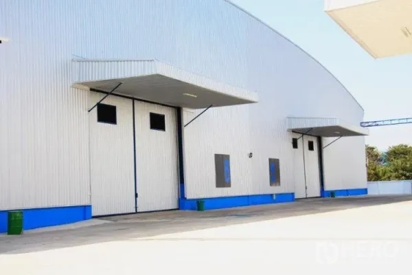 Warehouse for rent in Pathum Thani - Multiple roller doors and covered loading bays along a metal-clad warehouse facade.