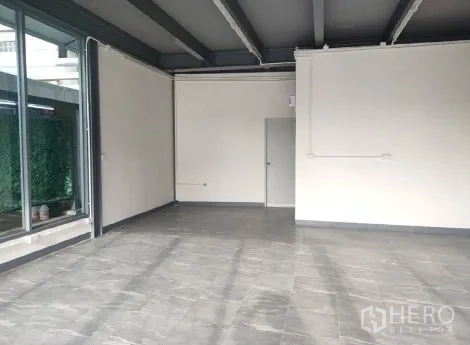 零售空间 出租在Khlong Toei, Bangkok - 宽敞室内，灰色地砖、天花梁与落地窗。