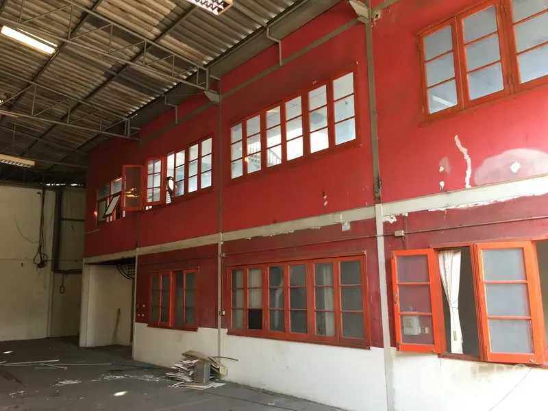 Warehouse for rent in Suan Luang, Bangkok - Two-storey internal office block with red facade and rows of windows overlooking the warehouse floor.