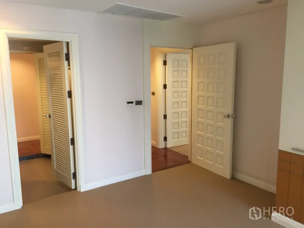 Condominium for rent in Pathum Wan, Bangkok - Bright hallway with multiple paneled doors and louvered closet in a Pathum Wan condominium.