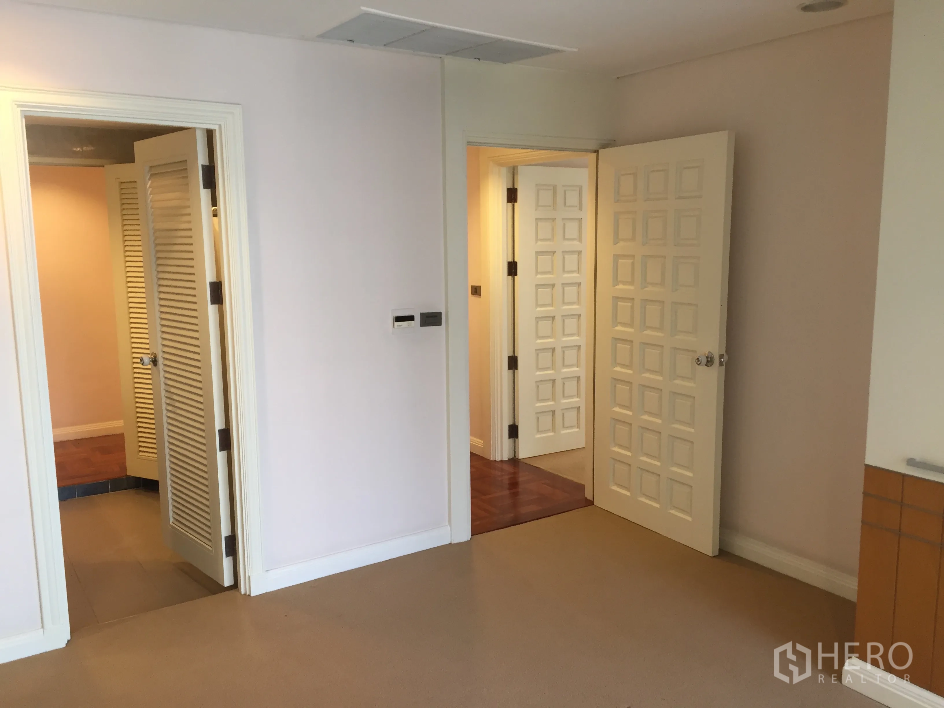 Condominium for rent in Pathum Wan, Bangkok - Bright hallway with multiple paneled doors and louvered closet in a Pathum Wan condominium.