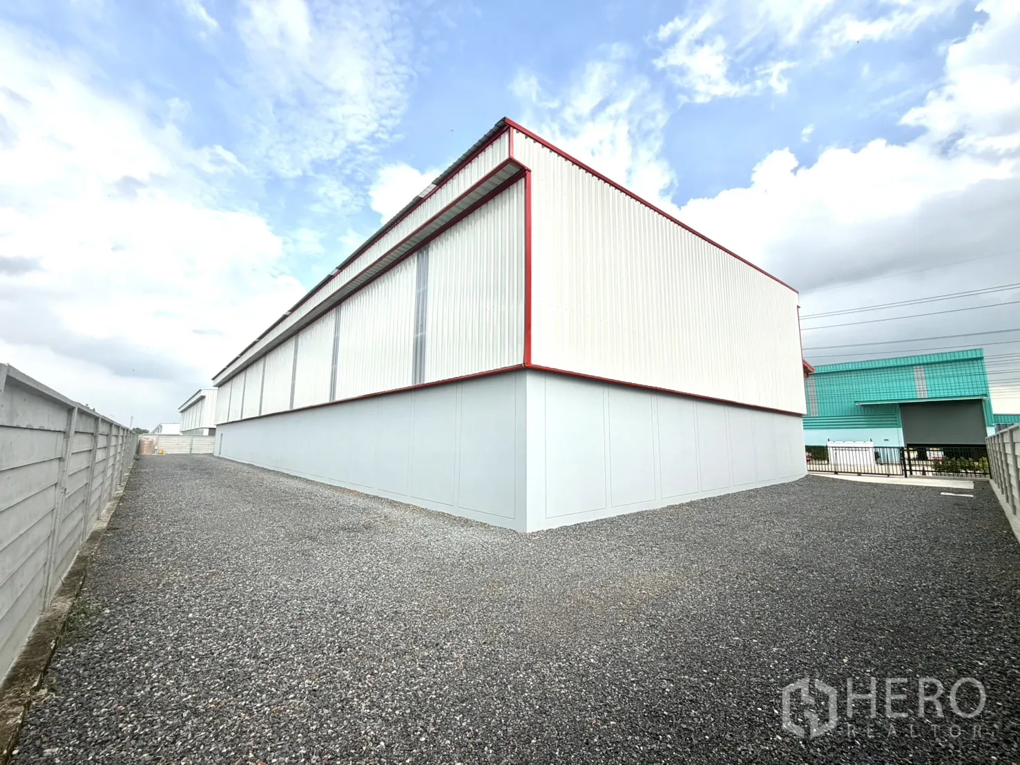 Factory for rent or sale in Lam Luk Ka, Pathum Thani - Wide gravel driveway running beside the warehouse and boundary wall.