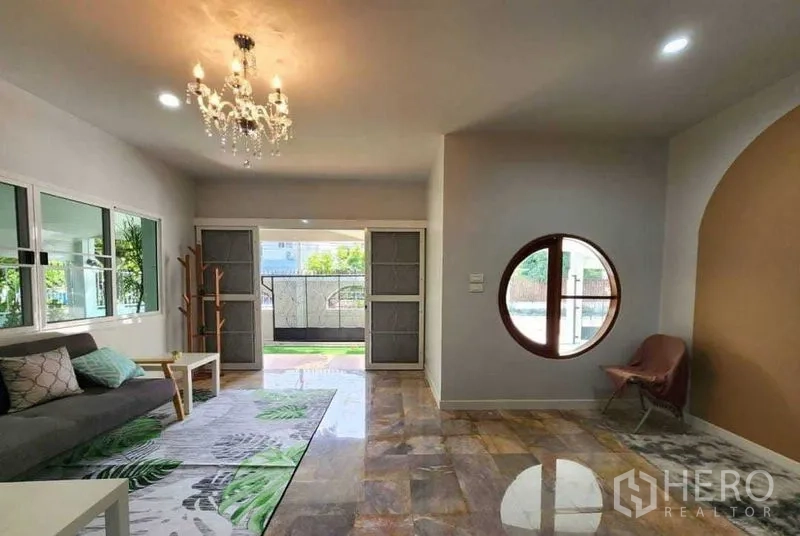 บ้าน ให้เช่าในLam Luk Ka, Pathum Thani - โถงรับแขกโปร่ง โคมระย้า หน้าต่างวงกลม และวิวสวน