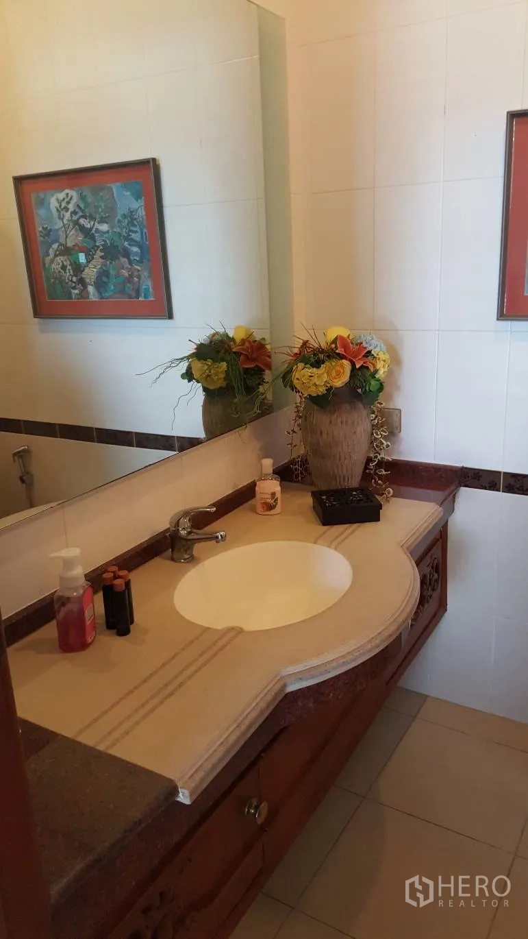 บ้าน ให้เช่าในKhlong Toei, Bangkok - ห้องน้ำปูกระเบื้อง เคาน์เตอร์ซิงก์หินพร้อมกระจกบานใหญ่และแจกันดอกไม้.