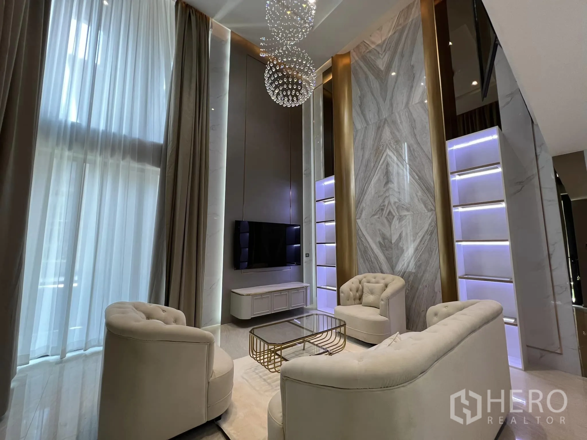 บ้าน ให้เช่าหรือขายในYan Nawa, Bangkok - ห้องนั่งเล่นเพดานสูงสองชั้น โซฟาหรู ทีวี และผนังหินอ่อน